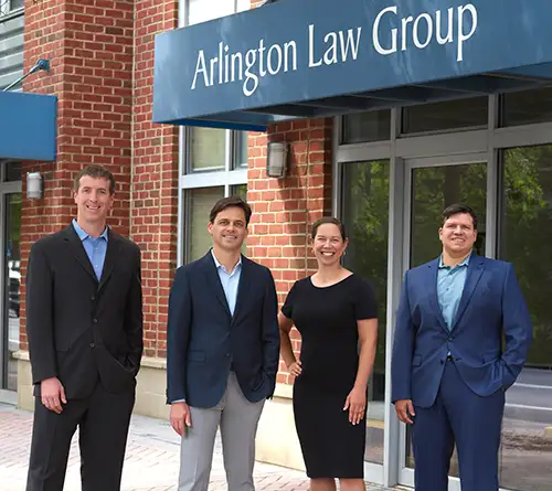 Storefront of Arlington Law Group with brick building, blue awning, and legal team in front